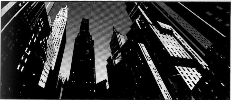 A low view up between skyscrapers at night.