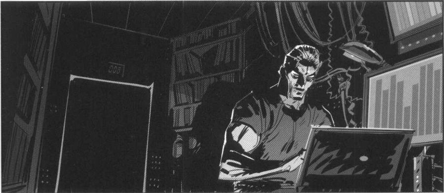 A man at a laptop in a dark room, a door on the left.